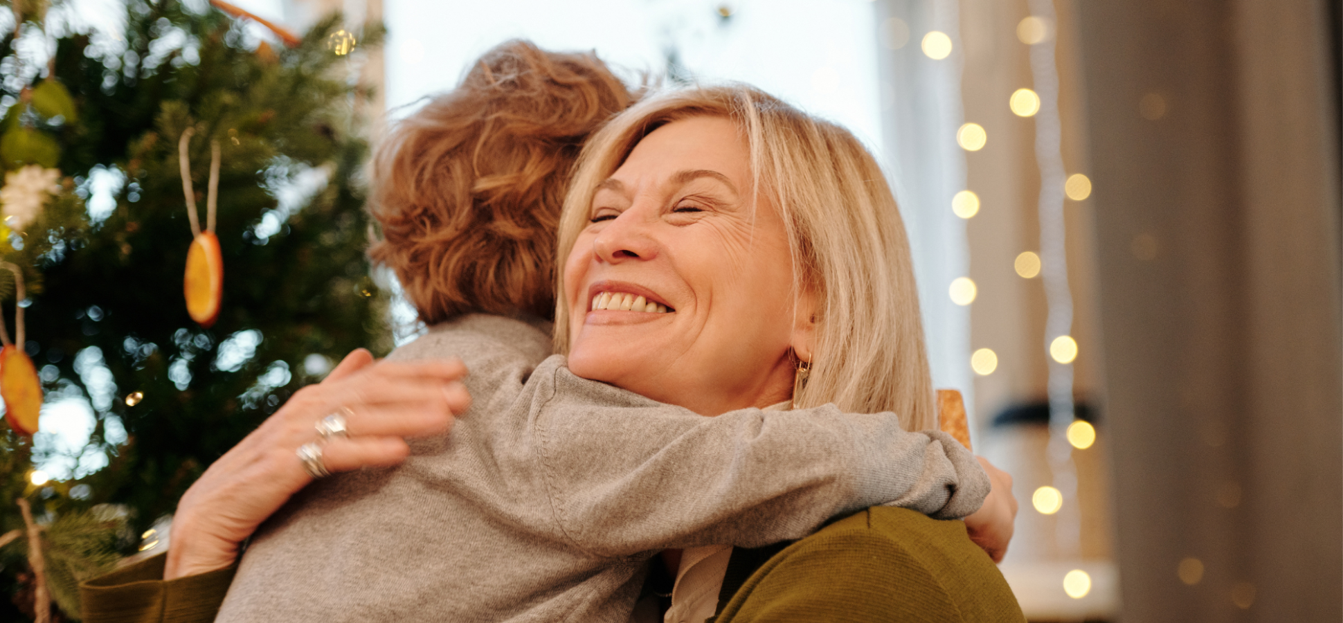 Mother hugging son in front of Christmas tree