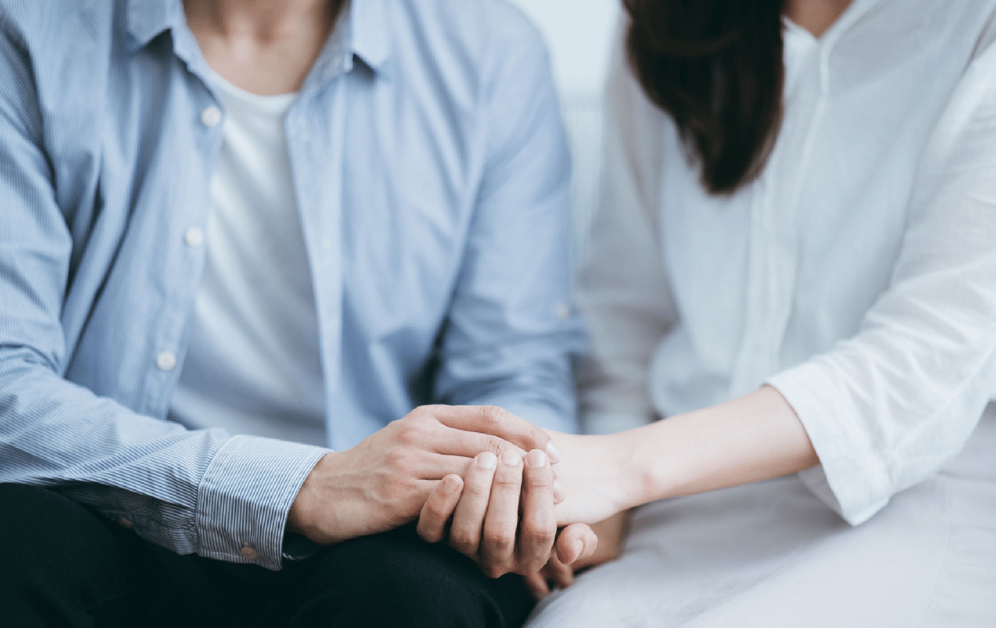 Two people holding one another's hands resting at lap level