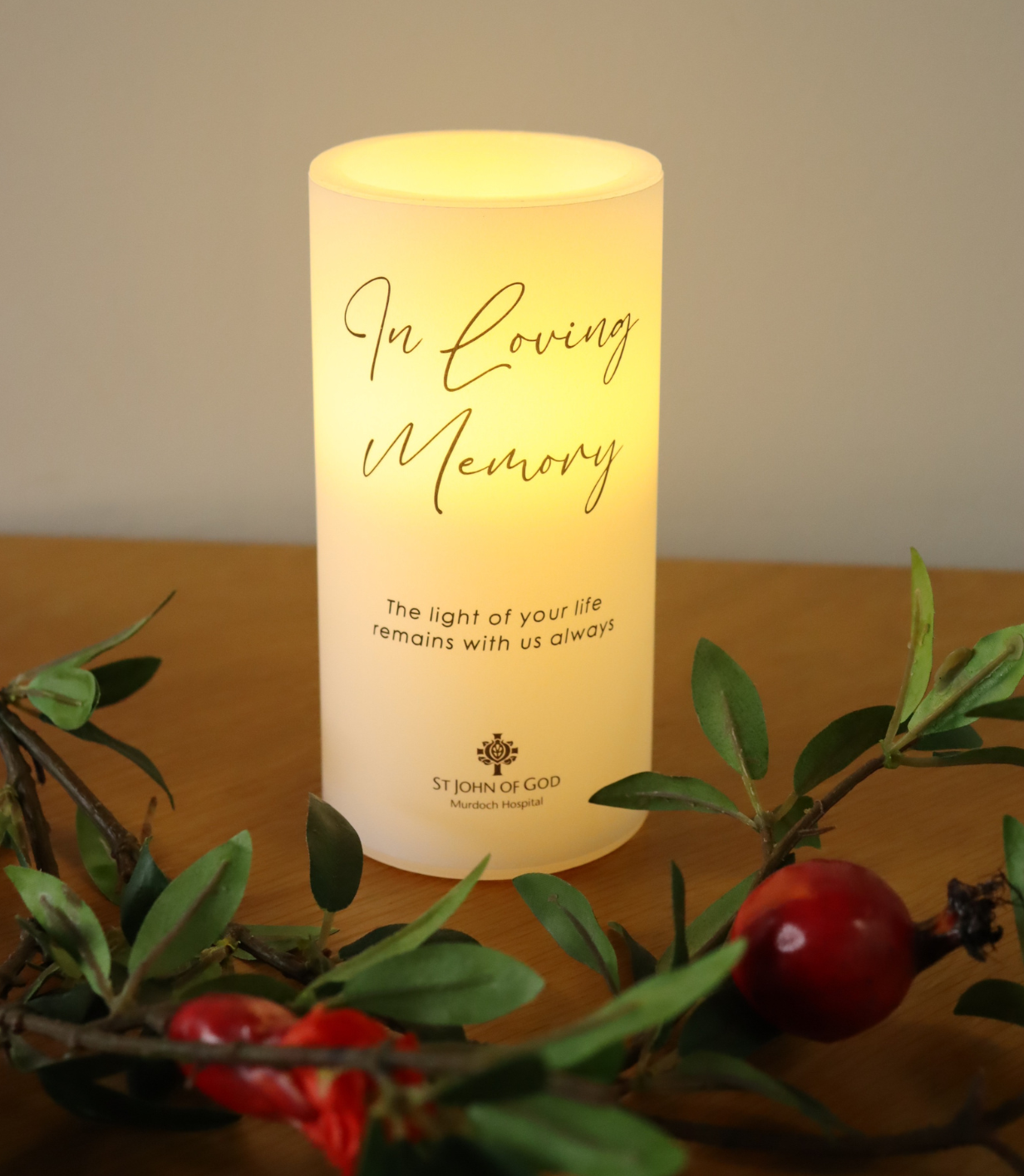 Glowing candle inscribed with the words: 'In loving memory - the light of your life remains with us always'