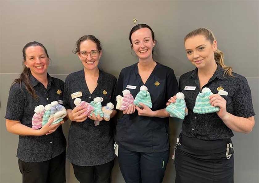 Four caregivers smile with the donated beanies