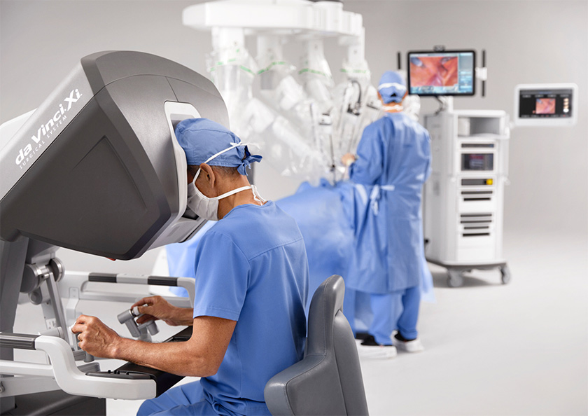 A surgeon in scrubs uses the da Vinci Xi robot