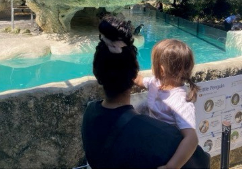 A mother holding her young daughter look out over the penguin enclosure