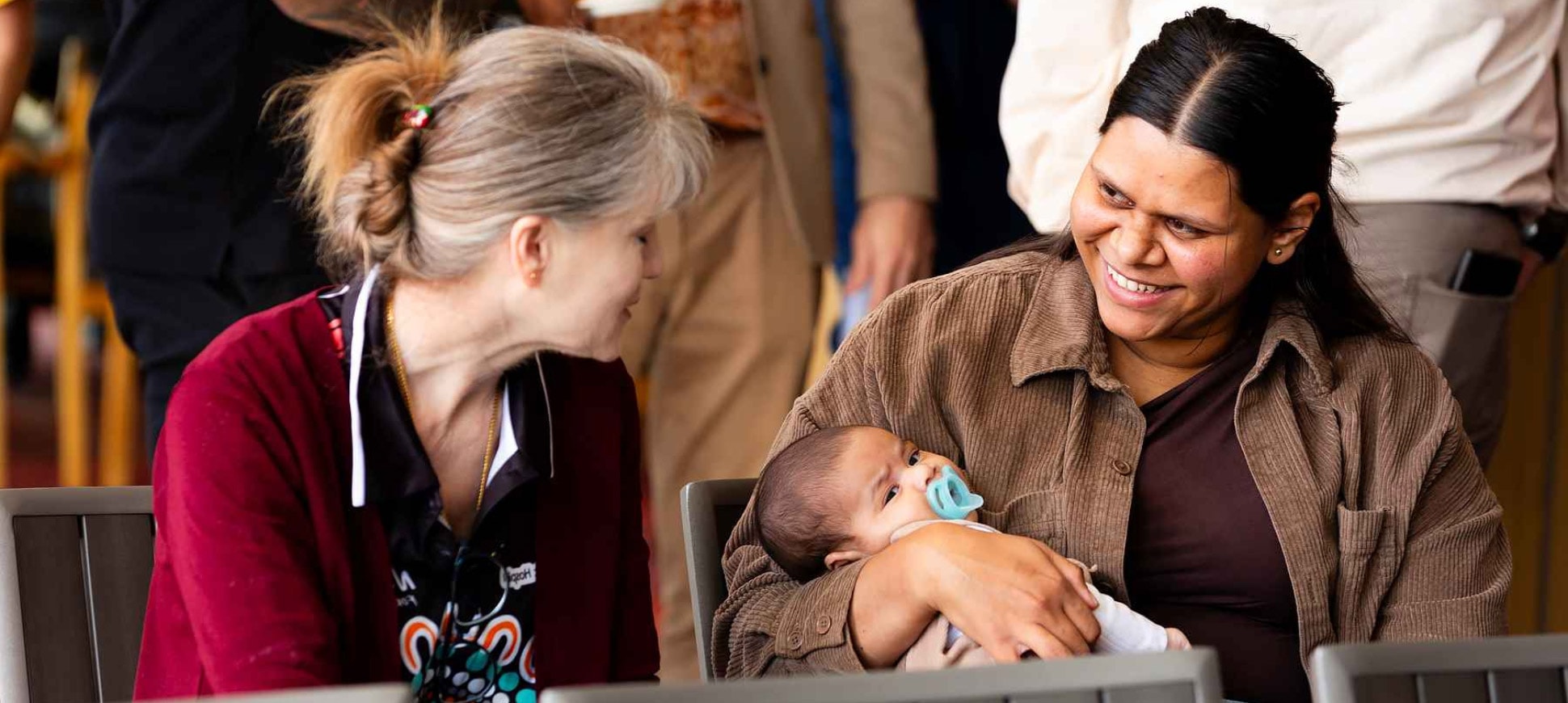 A Moort Boodjari Mia caregiver sits with a mother holding her baby