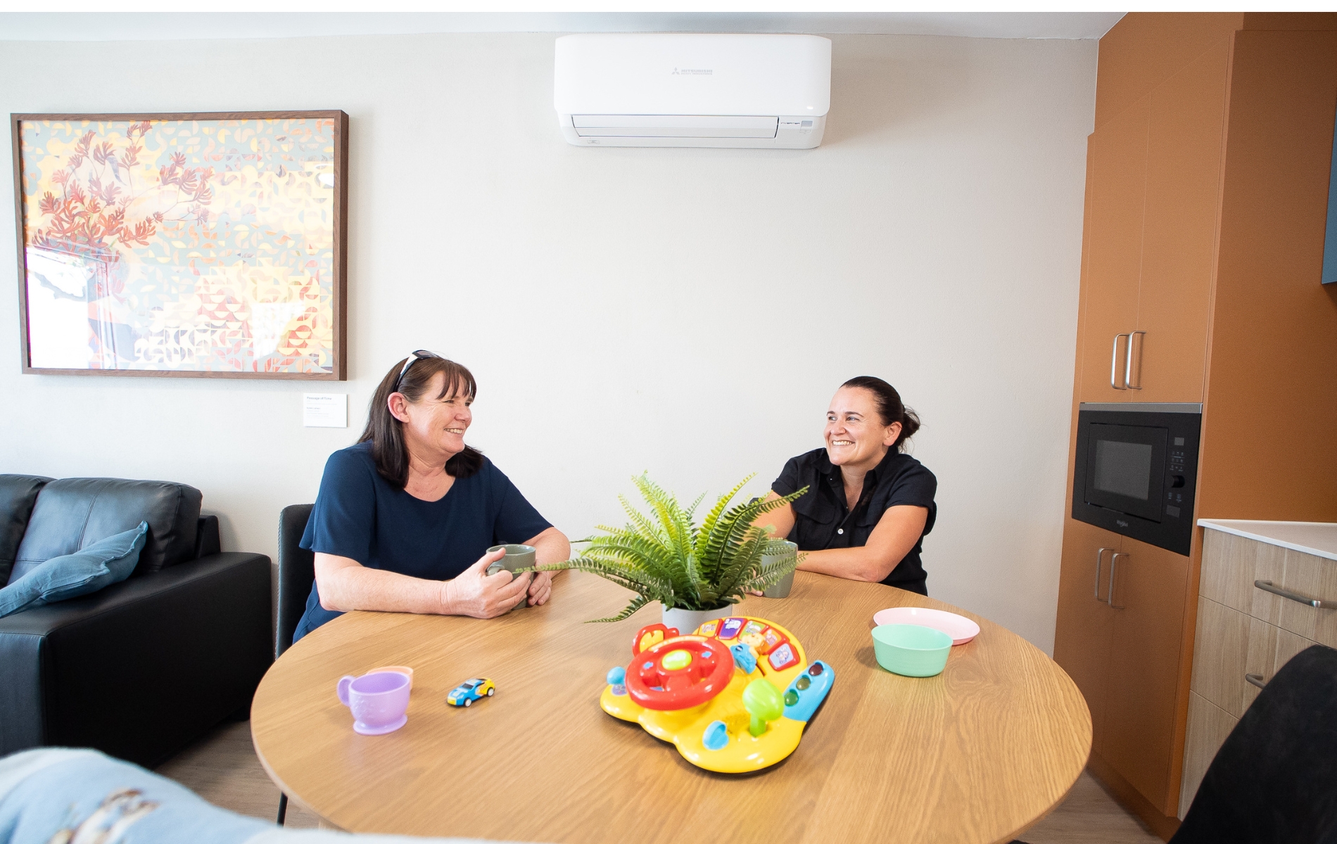 Two women sitting behind a table, talking to eachother