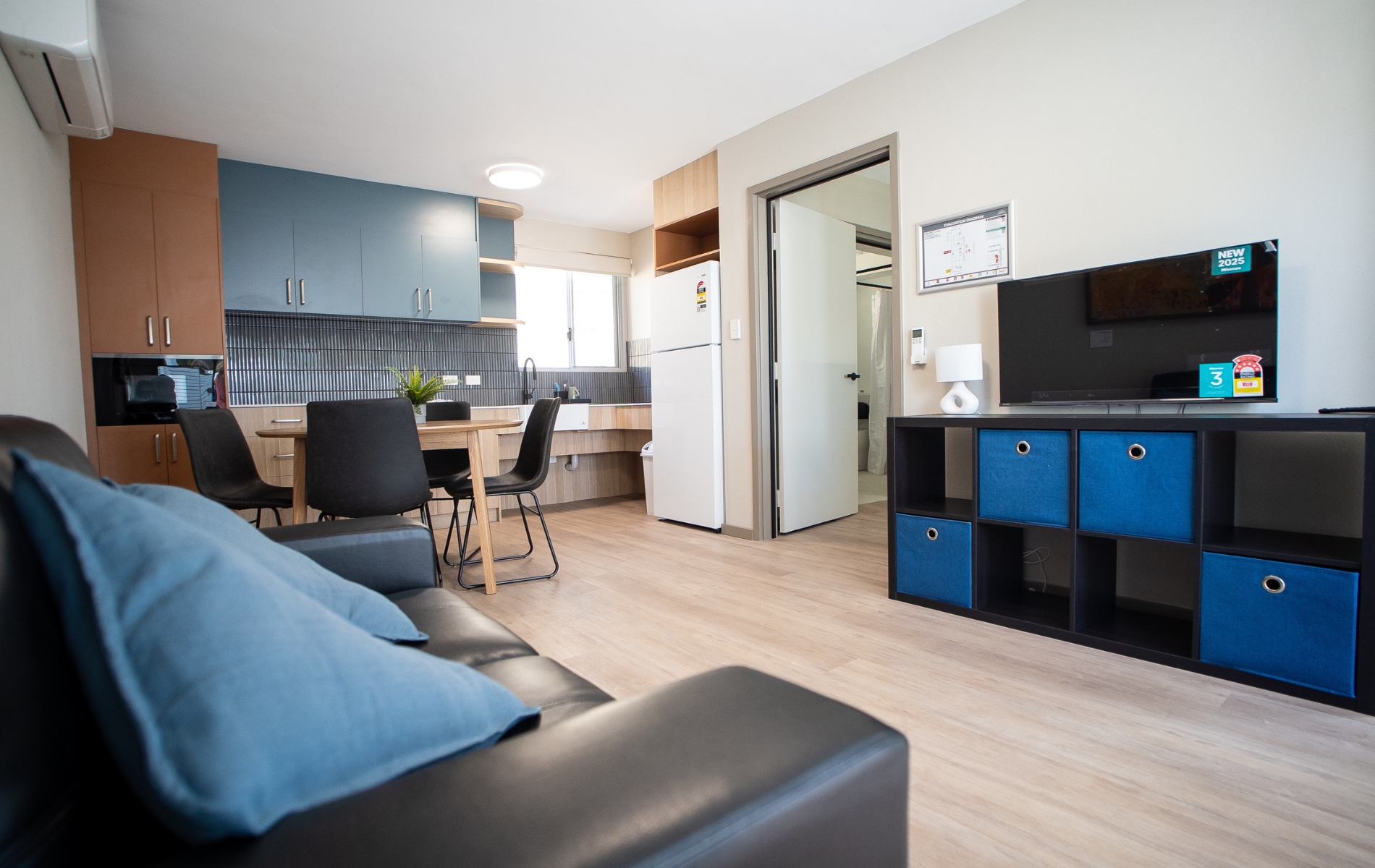 A modern looking room with a kitchen, couch, tv and dining table