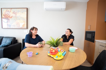 2 people sitting around a round table while chatting and having a warm drink