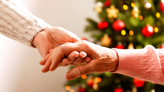Hands holding in front of Christmas Tree