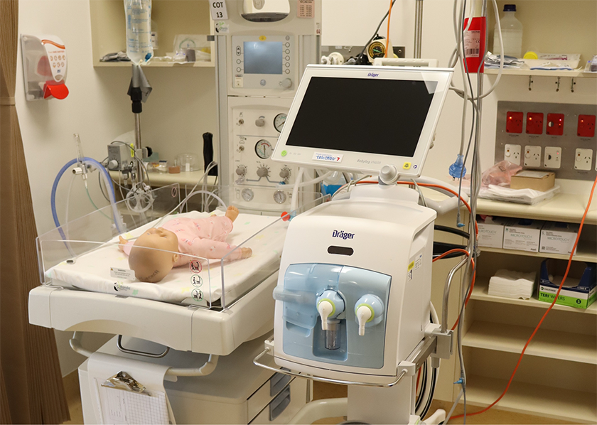 A new baby ventilator in a hospital room with a baby doll lying next to it.