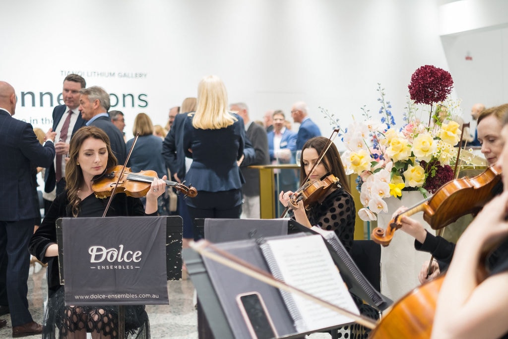 String quartet playing in room of people mingling at donor event