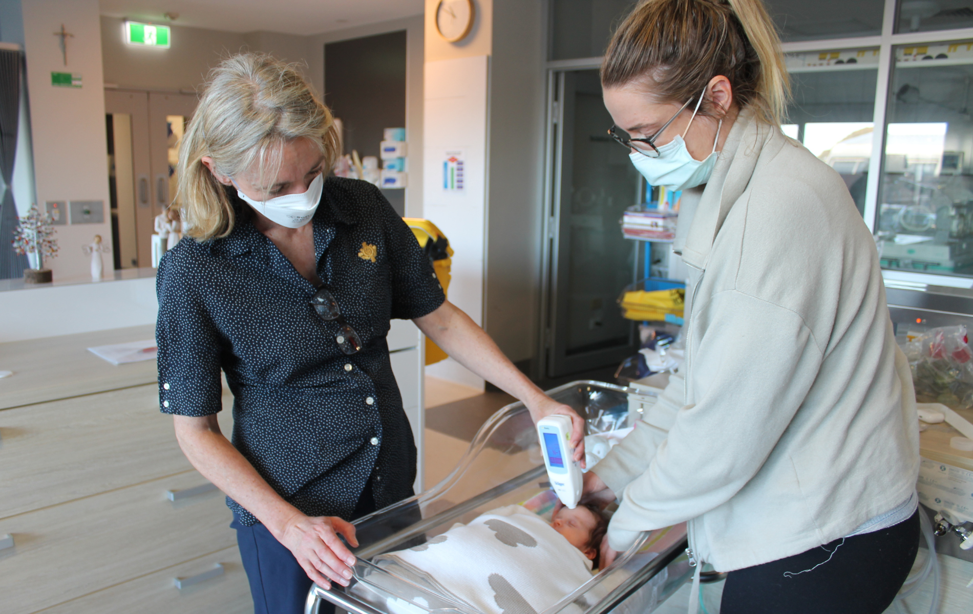 St John of God Geelong Hospital caregiver using the Transcutaneous Billirubinometer on a new baby as the baby's mother watches on