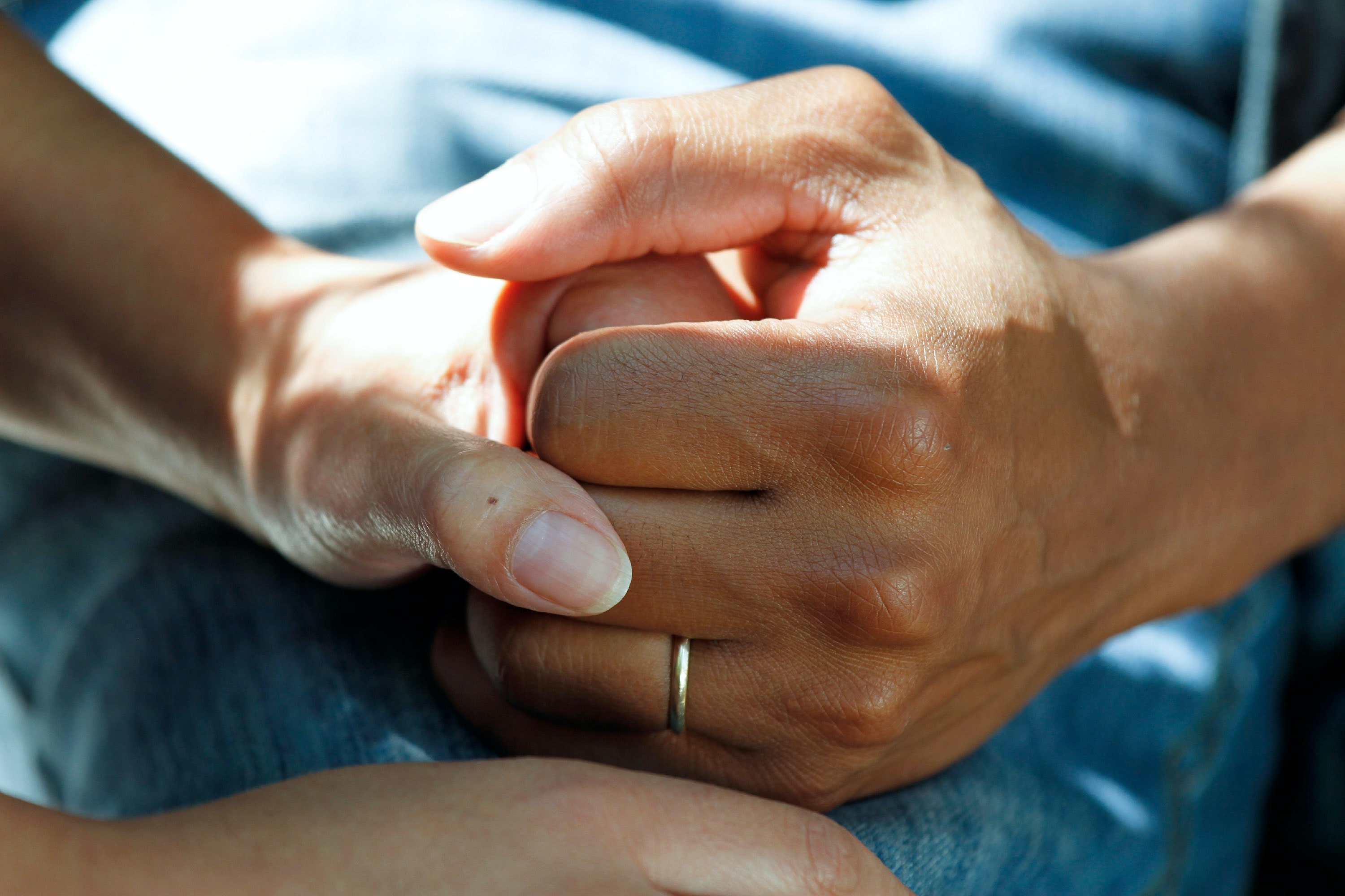 Close up of two people's hands holding each other in a comforting manner