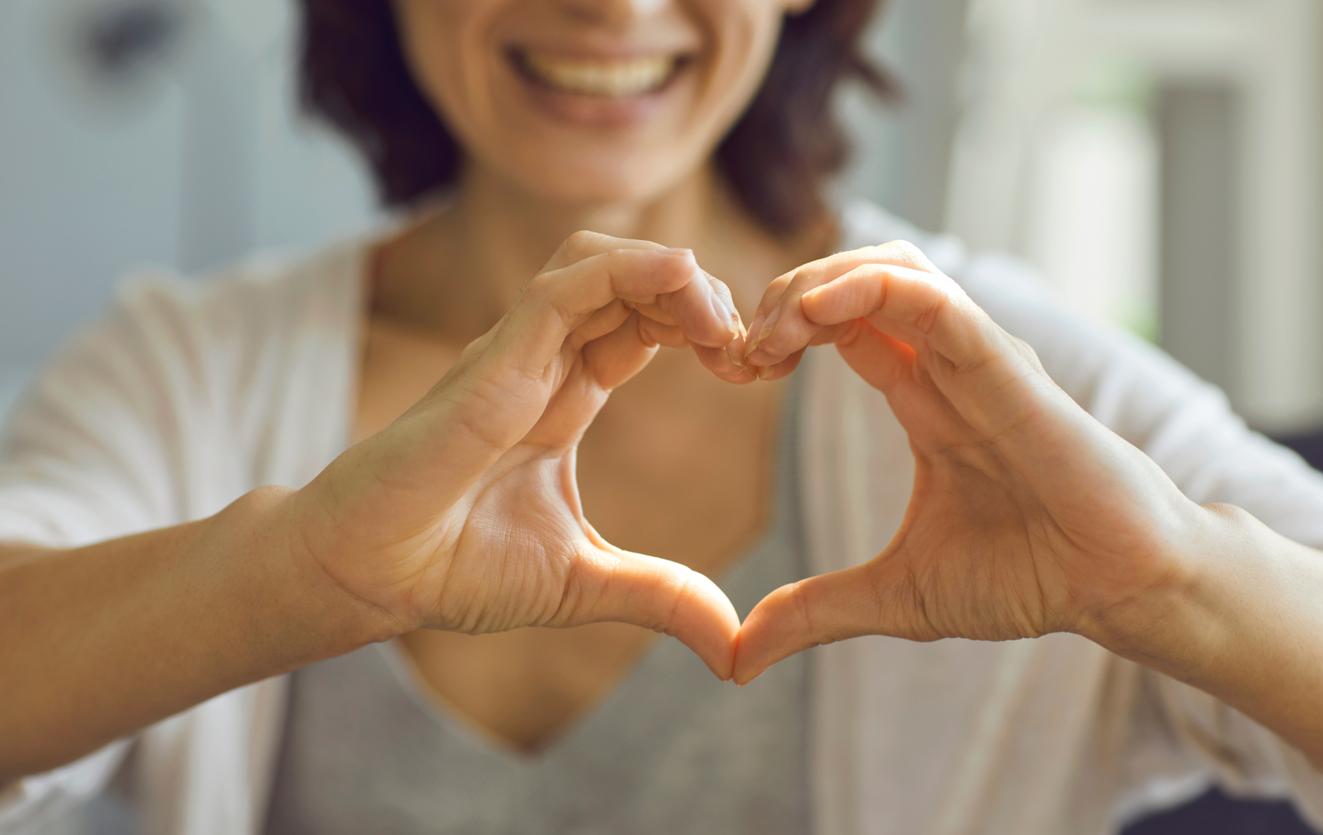Woman smiling holding her hands in the shape of the heart