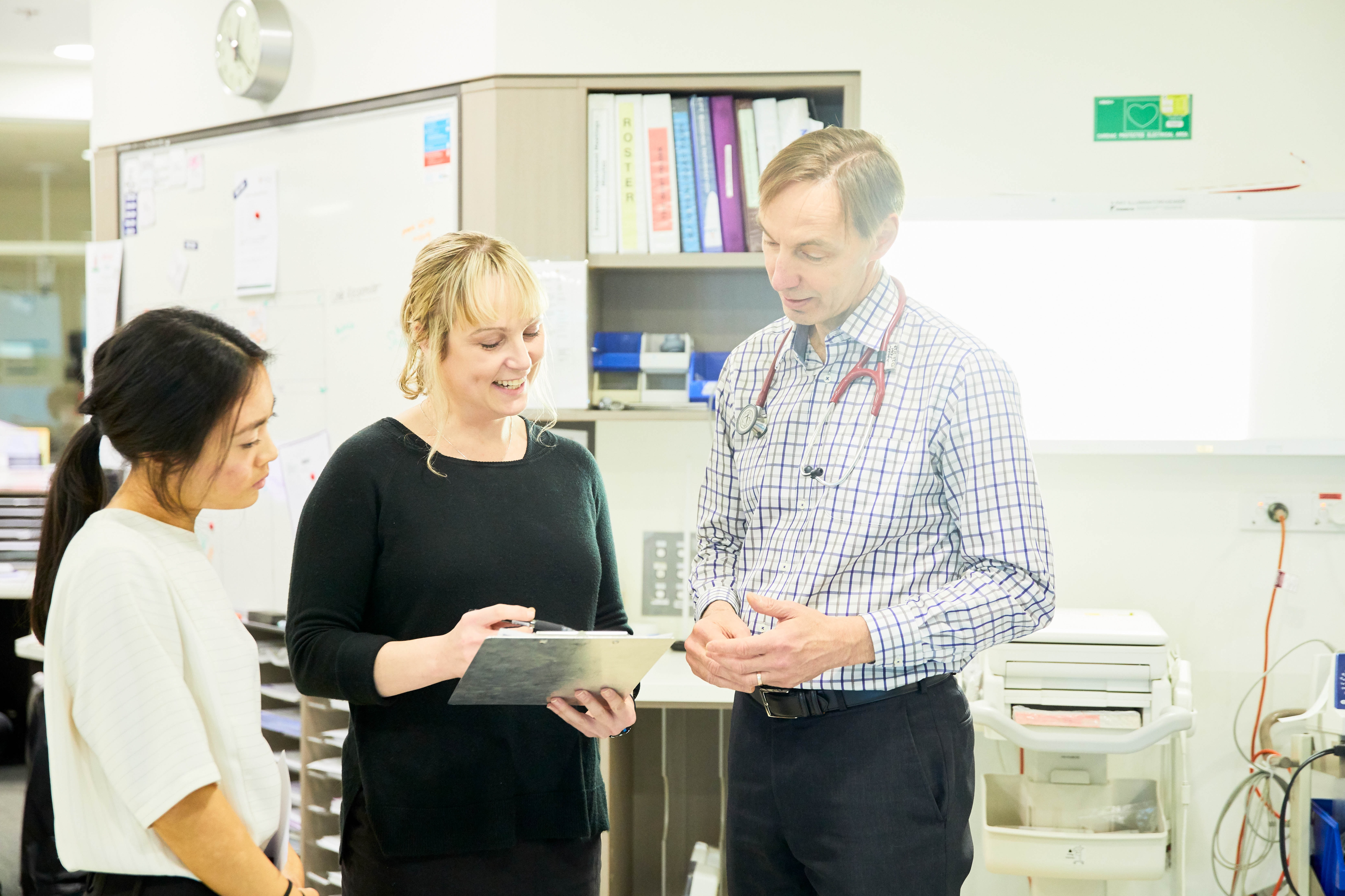 Three St John of God Ballarat hospital caregivers looking at clipboard and talking to each other