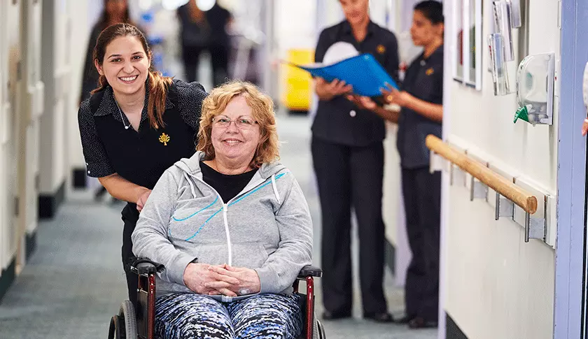 Caregiver pushing patient in wheelchair.