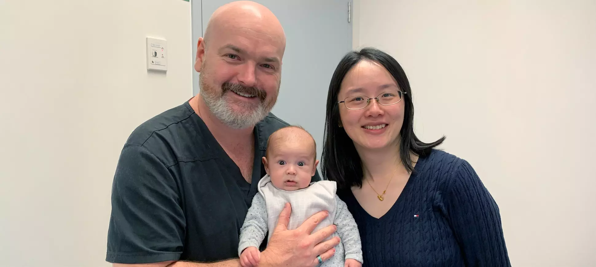 A man and a woman smiling while holding a baby.