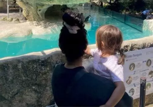 A mother holding her young daughter look out over the penguin enclosure.