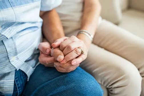 Older couple holding hands.