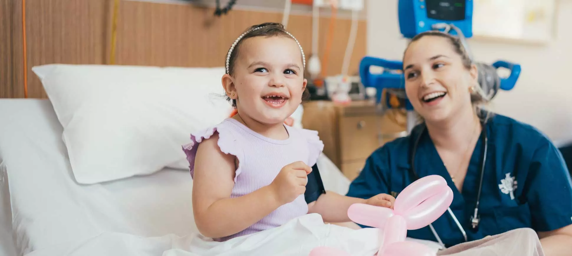 A caregiver and infant patient smile with a balloon animal.