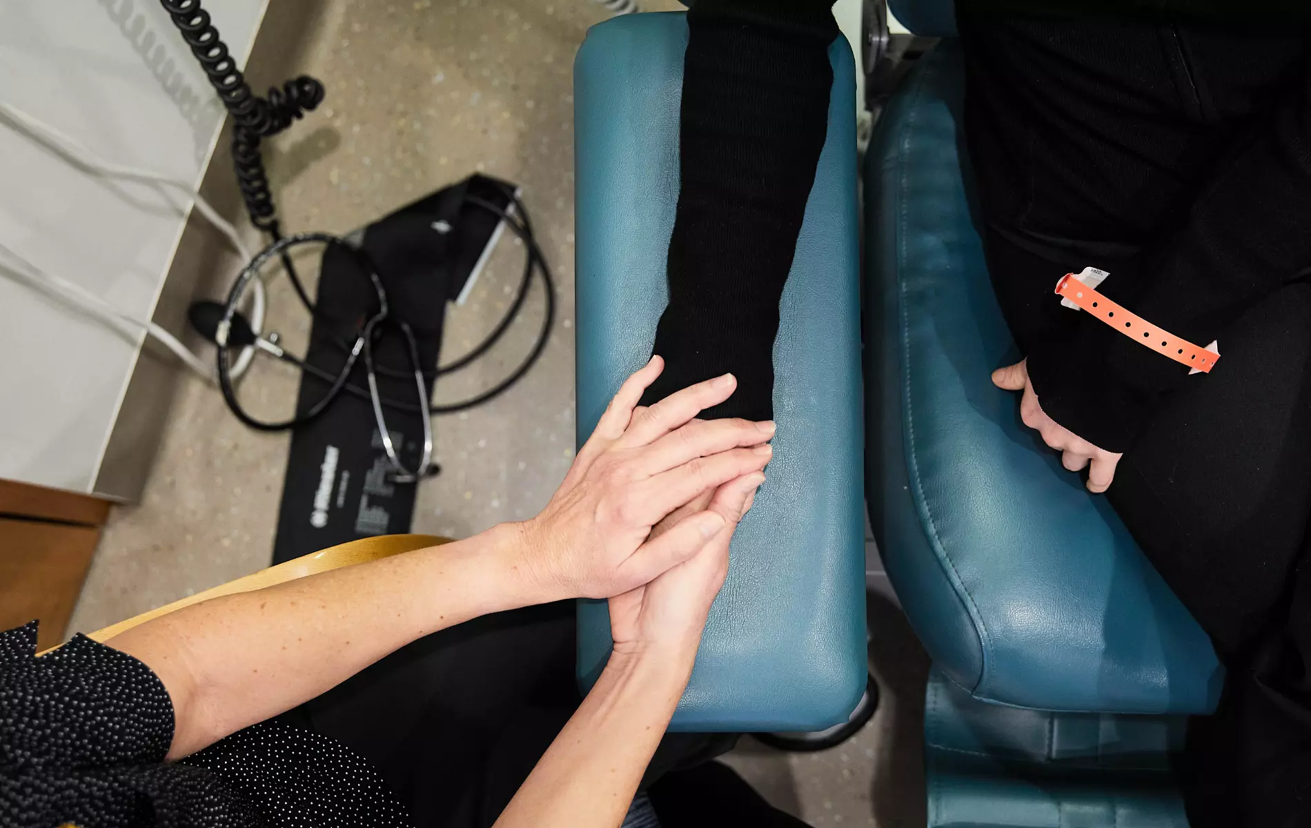 Cancer patient holding hands with caregiver.