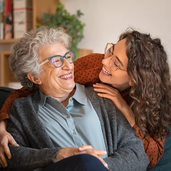 Older woman and younger woman hugging and smiling.