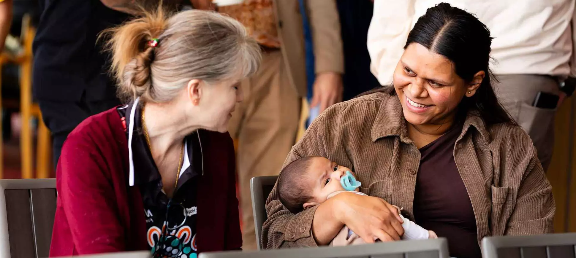 A Moort Boodjari Mia caregiver sits with a mother holding her baby.