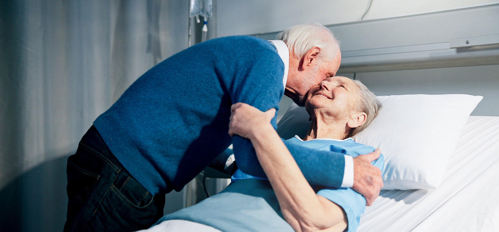 A person hugging a patient in a hospital bed