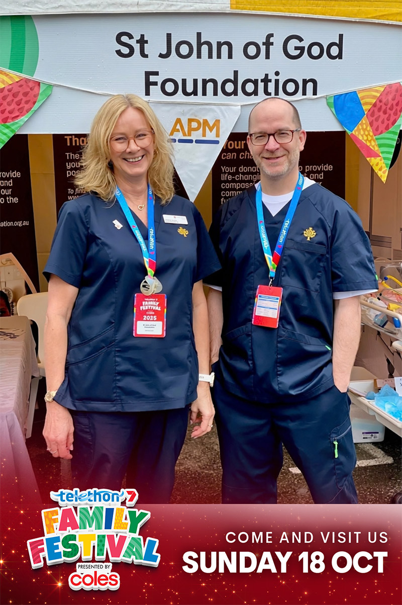 Two medical caregivers dressed in scrubs smile at the Foundation booth