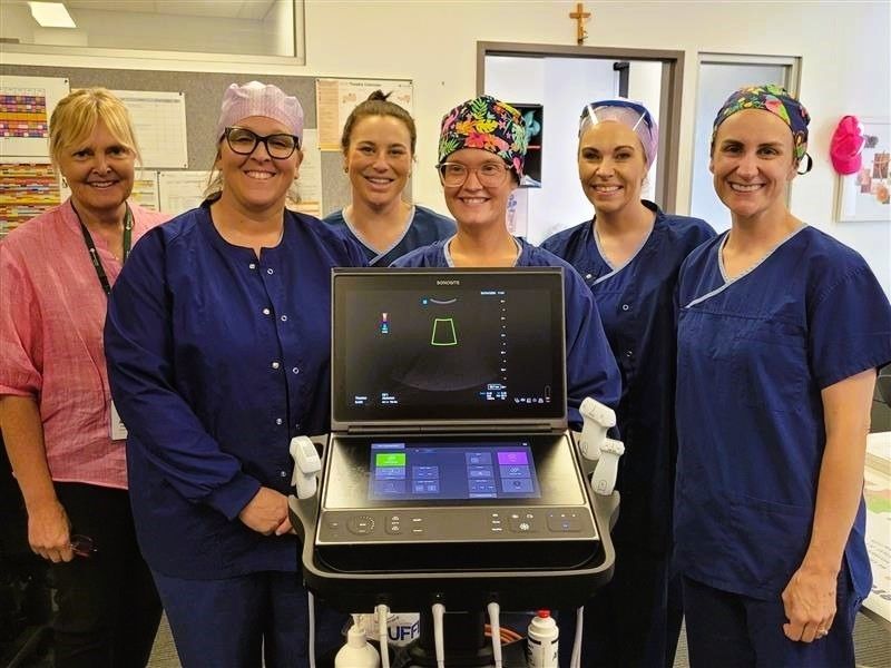 Six caregivers standing with an ultrasound machine