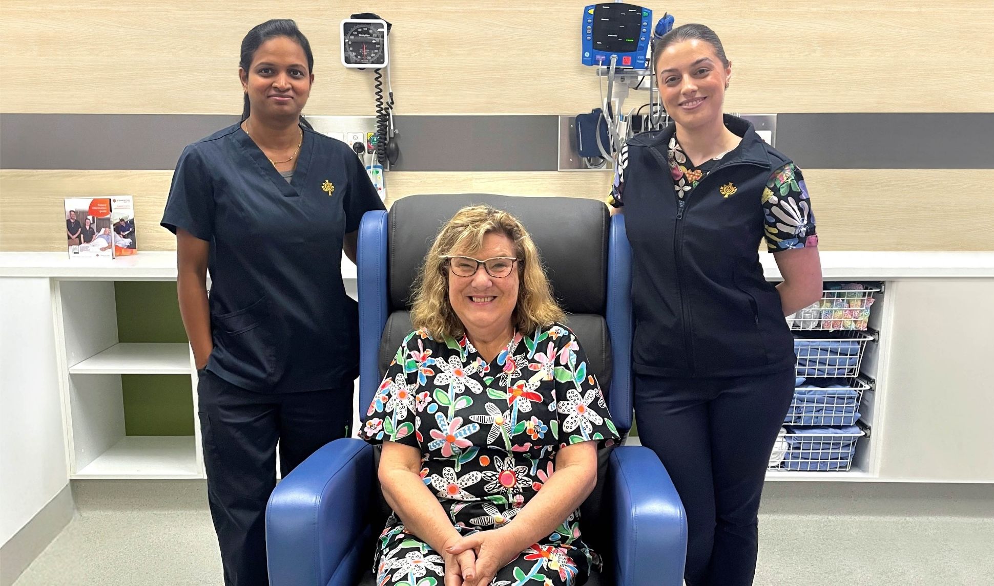 A person sitting in a recliner, with two caregivers standing behind.
