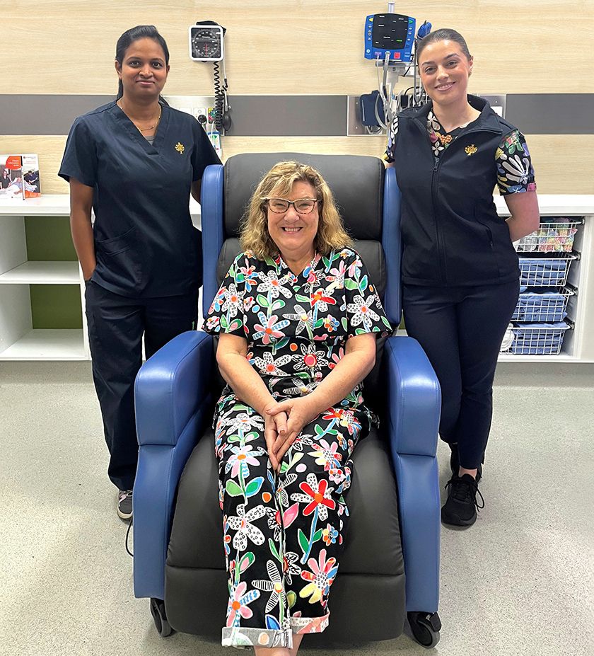 A person sitting in a recliner, with two caregivers standing behind.
