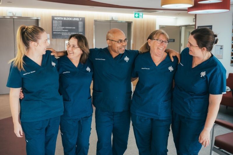 Five caregivers in blude scrubs standing together
